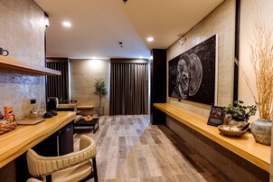 Una cocina moderna con encimera de madera, zona de comedor con una silla, cafetera y un cuadro grande en la pared.