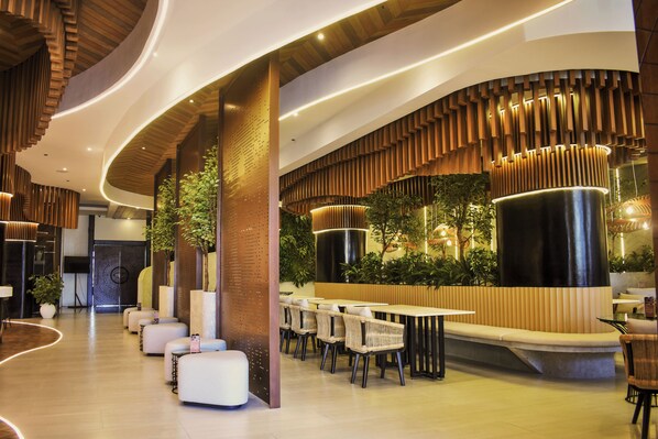A modern indoor space with a curved ceiling, seating areas, and a wall with vertical wooden slats. - Azzurro Hotel (Angeles City)
