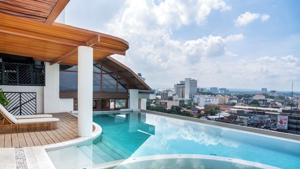A rooftop infinity pool with a wooden deck and a city view. - Azzurro Hotel (Angeles City)