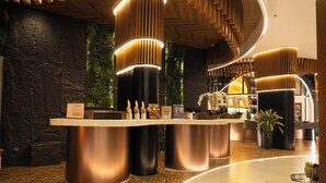 A reception area with a curved counter, modern pendant lighting, and a stone wall backdrop. - Azzurro Hotel (Angeles City)