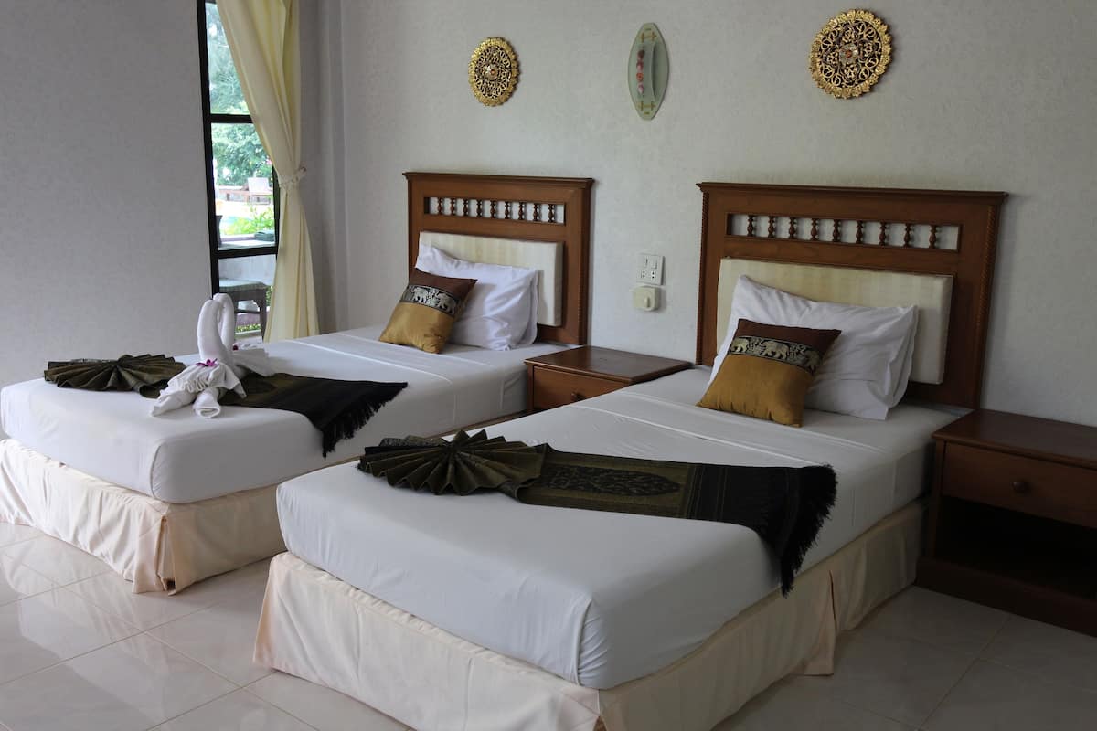 Two twin beds with wooden headboards, white bedding, and decorative pillows.