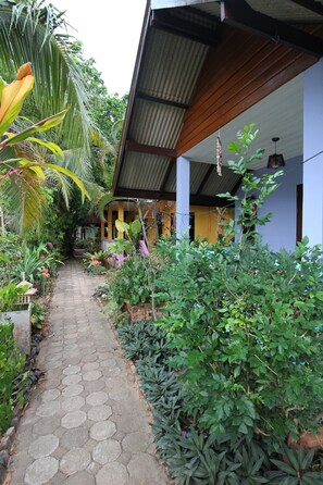 A pathway leading to a building with a covered porch, surrounded by lush greenery and various plants. - Lanta Villa Resort (Ko Lanta)