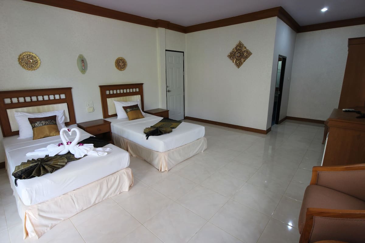 A hotel room with two beds, a wooden headboard, a desk, and a chair.