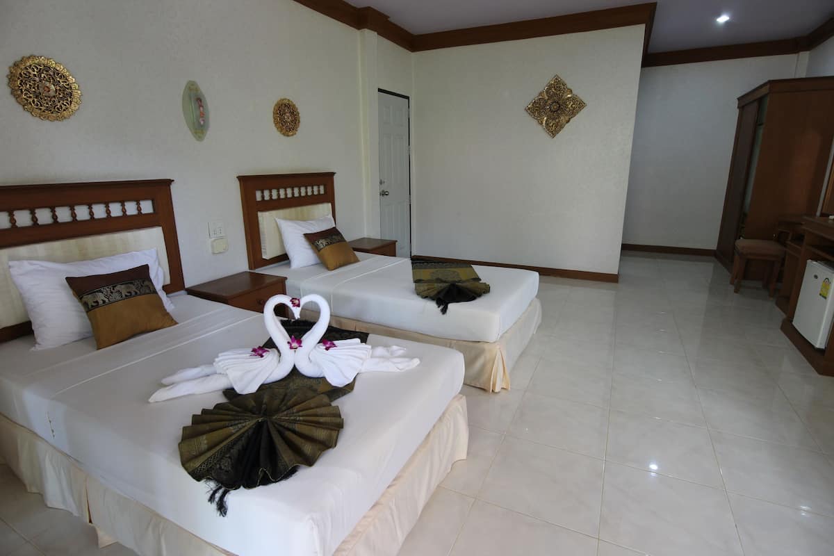 A hotel room with two beds, each with a headboard, a bedside table, and a decorative wall hanging.