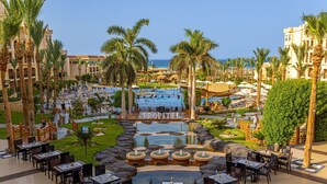 A resort with a central pool, outdoor dining area, and palm trees. - Tropitel Sahl Hasheesh Resort (Sahl Hasheeh)