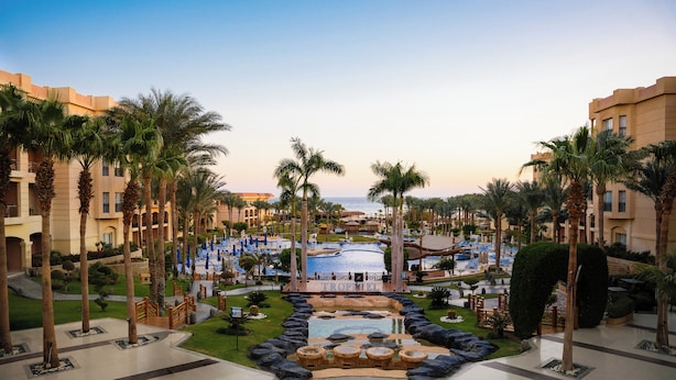 A resort with a central pool, palm trees, and a view of the sea. - Tropitel Sahl Hasheesh Resort (Sahl Hasheeh)