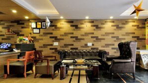 Eine moderne Lobby mit Ledersofa, Holzstühlen, einem Empfangstresen und einer Wand mit Muster.