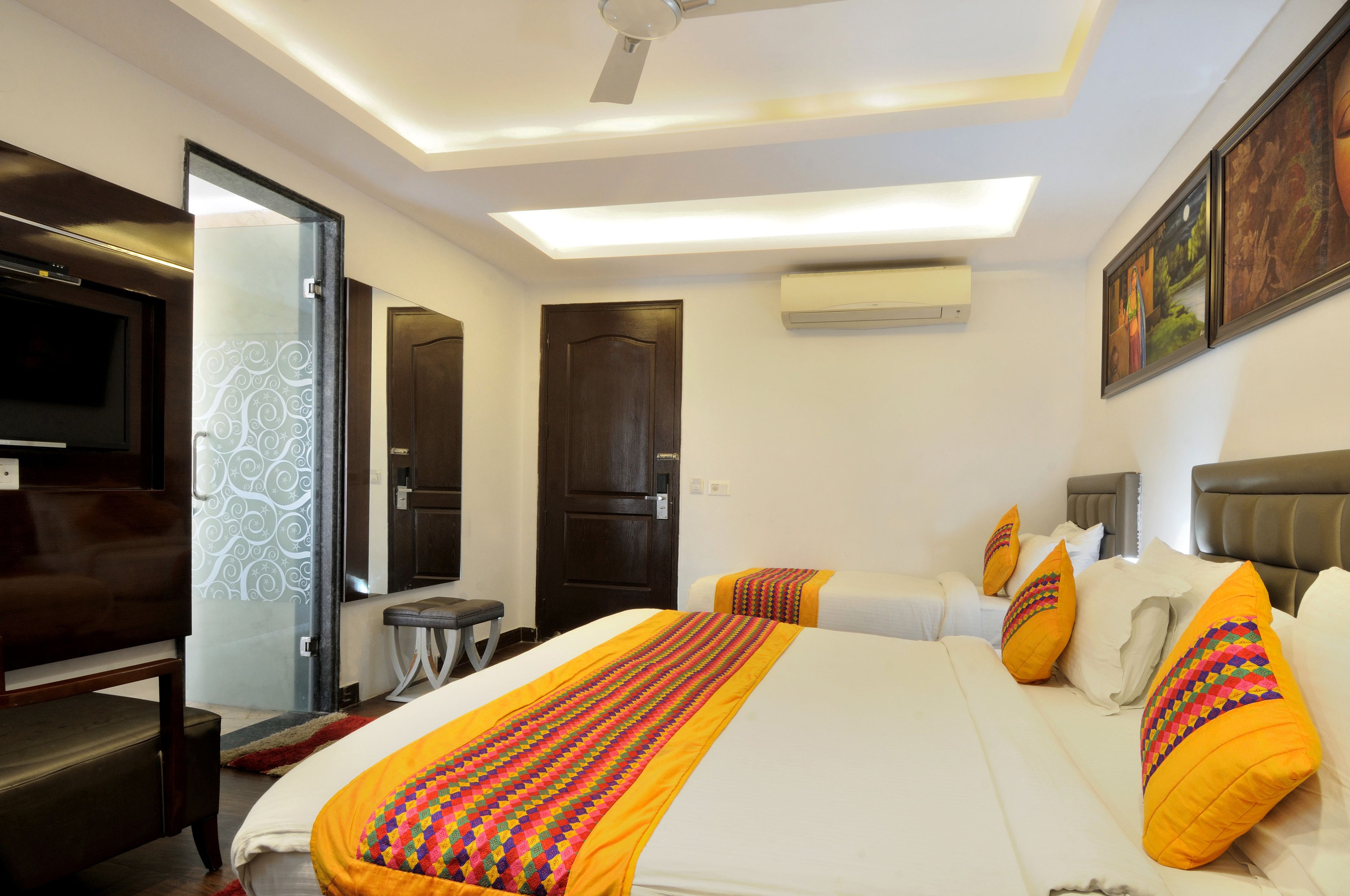 A hotel room with a large bed, a TV, a desk, and a door leading to a bathroom.