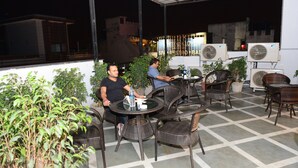 Eine Außenpatio-Terrasse mit Korbstühlen, Tischen, Topfpflanzen und Klimaanlagen.
