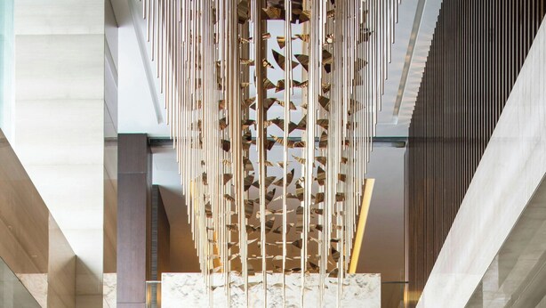 Un vestíbulo moderno con una columna de mármol, techo de listones de madera y diseño minimalista.