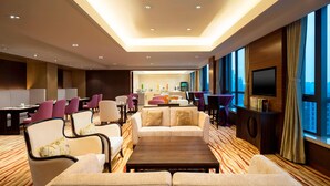 Un hall de hotel con zona de estar, una recepción y una pantalla de televisión grande.