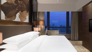 Habitación de hotel con una cama grande, televisor de pantalla plana, vista a la ciudad y diseño moderno.