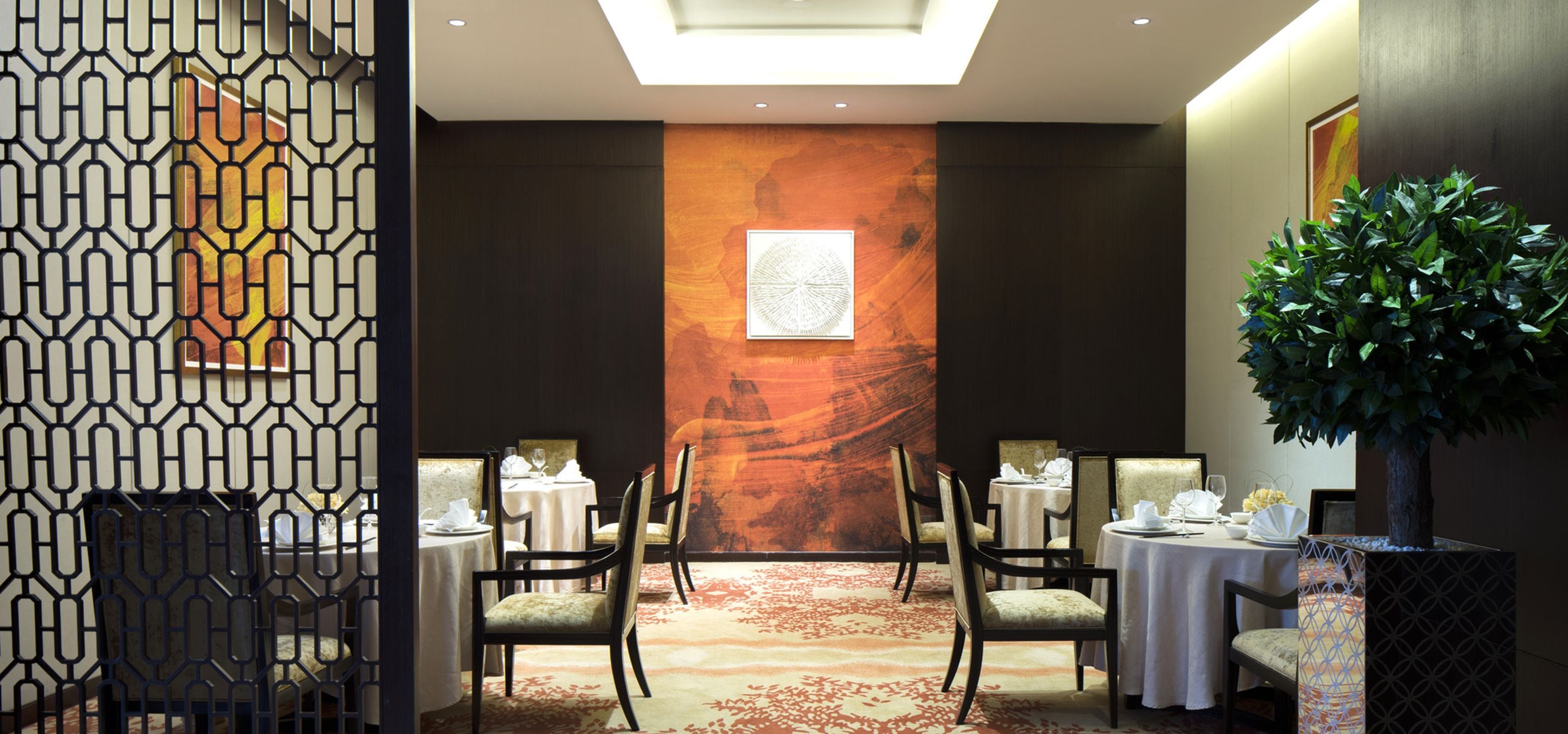 A conference room with a high ceiling, a large abstract mural, and a central table with chairs.