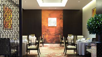 A conference room with a high ceiling, a large abstract mural, and a central table with chairs.