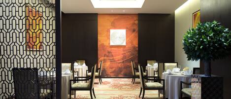A conference room with a high ceiling, a large abstract mural, and a central table with chairs.