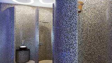 A modern bathroom with mosaic tile walls, a central sink, and circular ceiling lights.