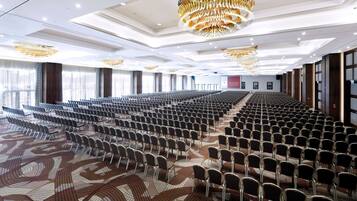 A large conference room with rows of chairs, a patterned carpet, and a modern chandelier.
