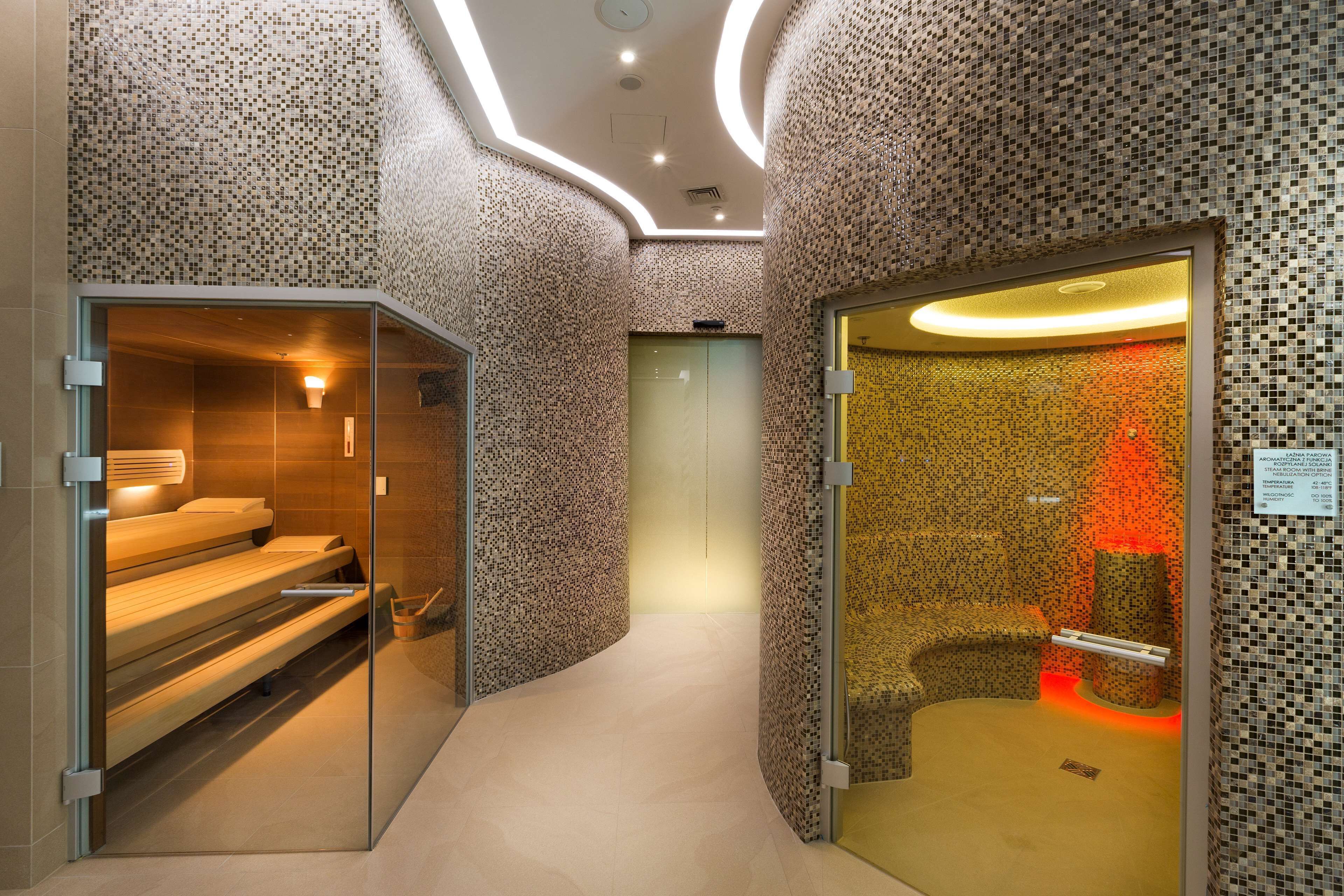 A modern spa with a glass-enclosed sauna, a massage room, and a relaxation area with a massage table.