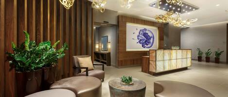 Un vestíbulo moderno con mostrador de recepción, zona de estar e iluminación decorativa.
