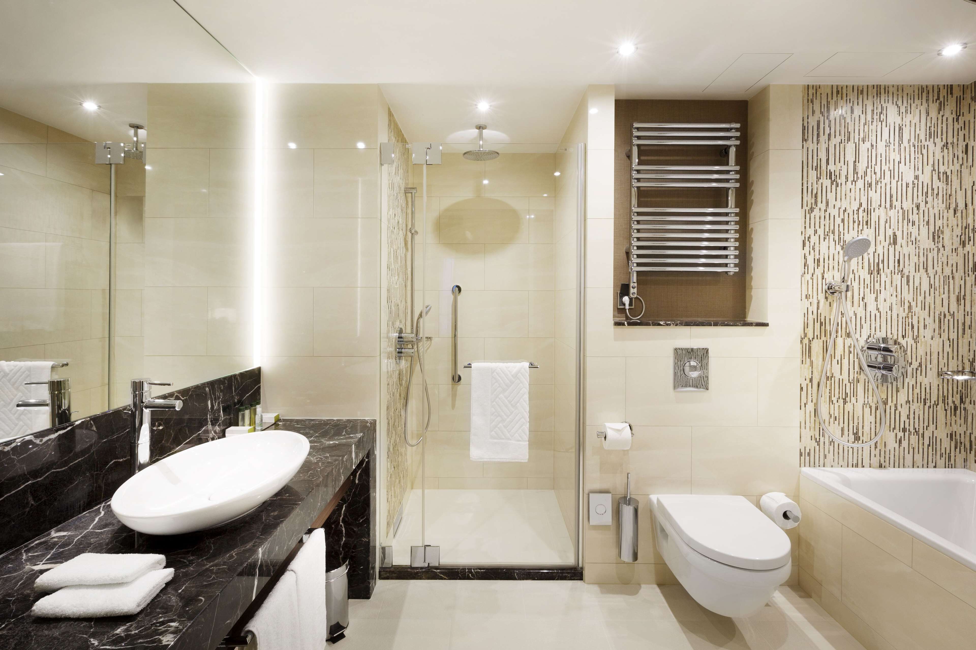 Une salle de bain moderne avec un grand lavabo ovale, une douche à parois de verre, des toilettes et une baignoire.