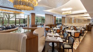 A spacious restaurant with high ceilings, modern chandeliers, and a view of the outdoors. - DoubleTree By Hilton Hotel & Conference Centre Warsaw (Warsaw)