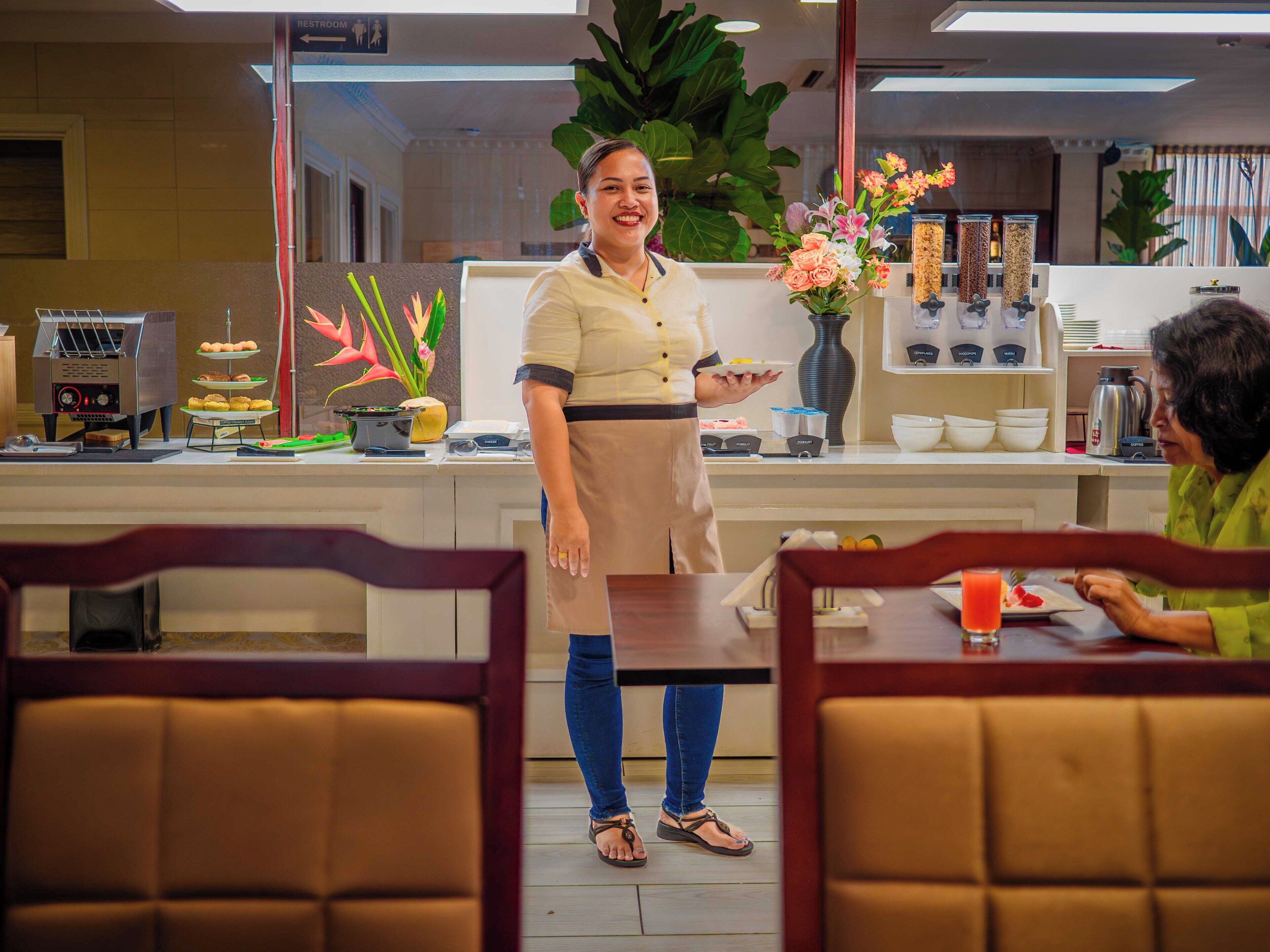 Un restaurante con mostrador, un cliente sentado en una mesa y un camarero detrás del mostrador.