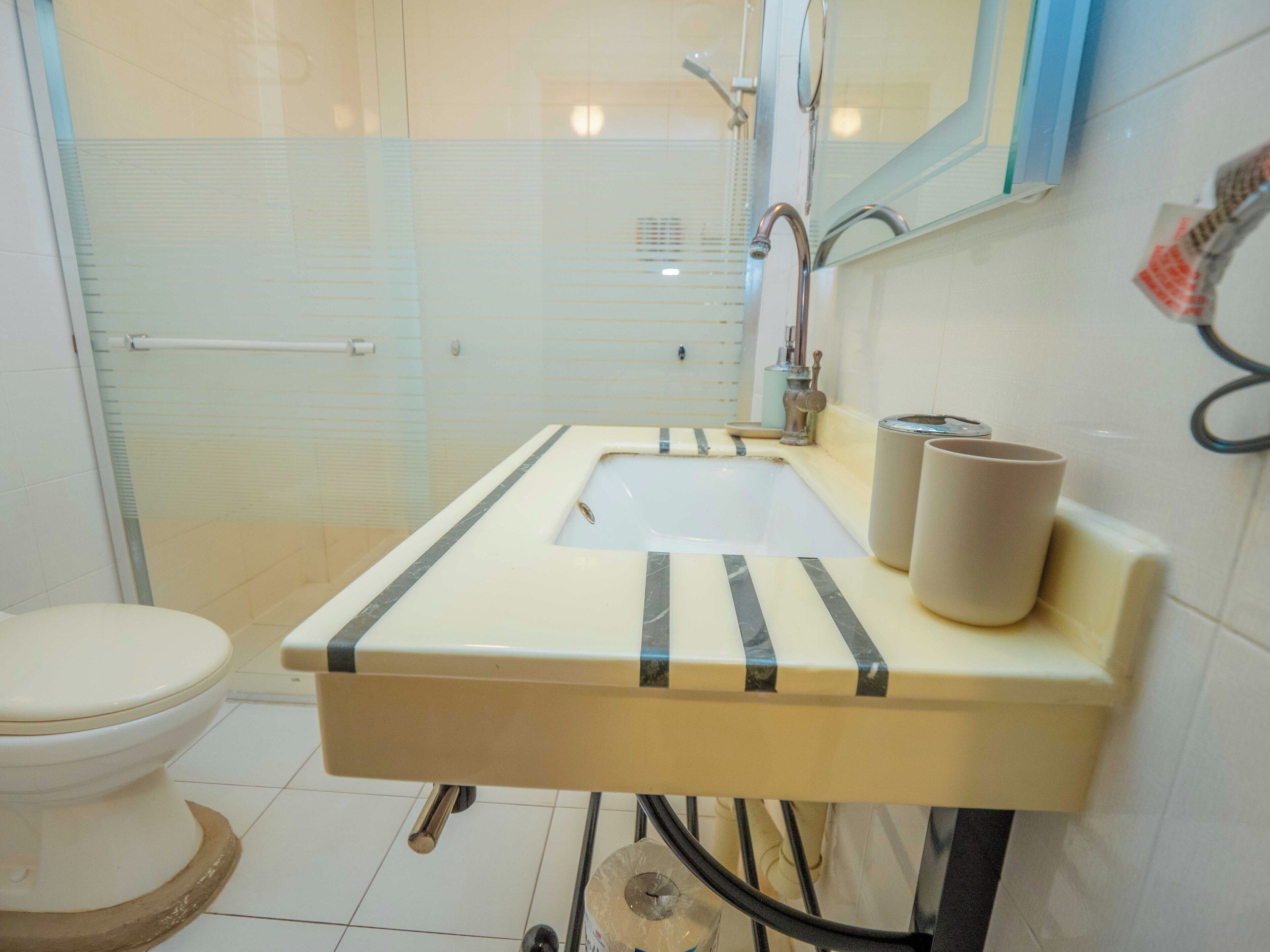 Un bagno con il water, un lavandino con specchio e zona doccia.