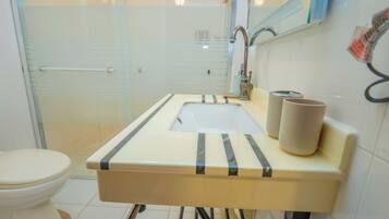 Un bagno con il water, un lavandino con specchio e zona doccia.