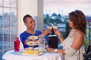 A table with a pitcher, cupcakes, and a red bottle. - Hotel Palacio (Paramaribo)