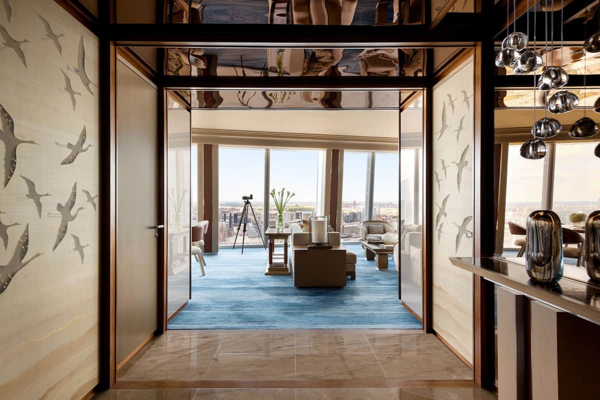A spacious room with a large window, a blue carpet, and a view of the city.