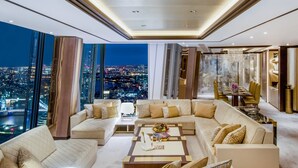A modern living room with a large sectional sofa, a coffee table, and a view of a cityscape at night. - Shangri-La The Shard, London (London)