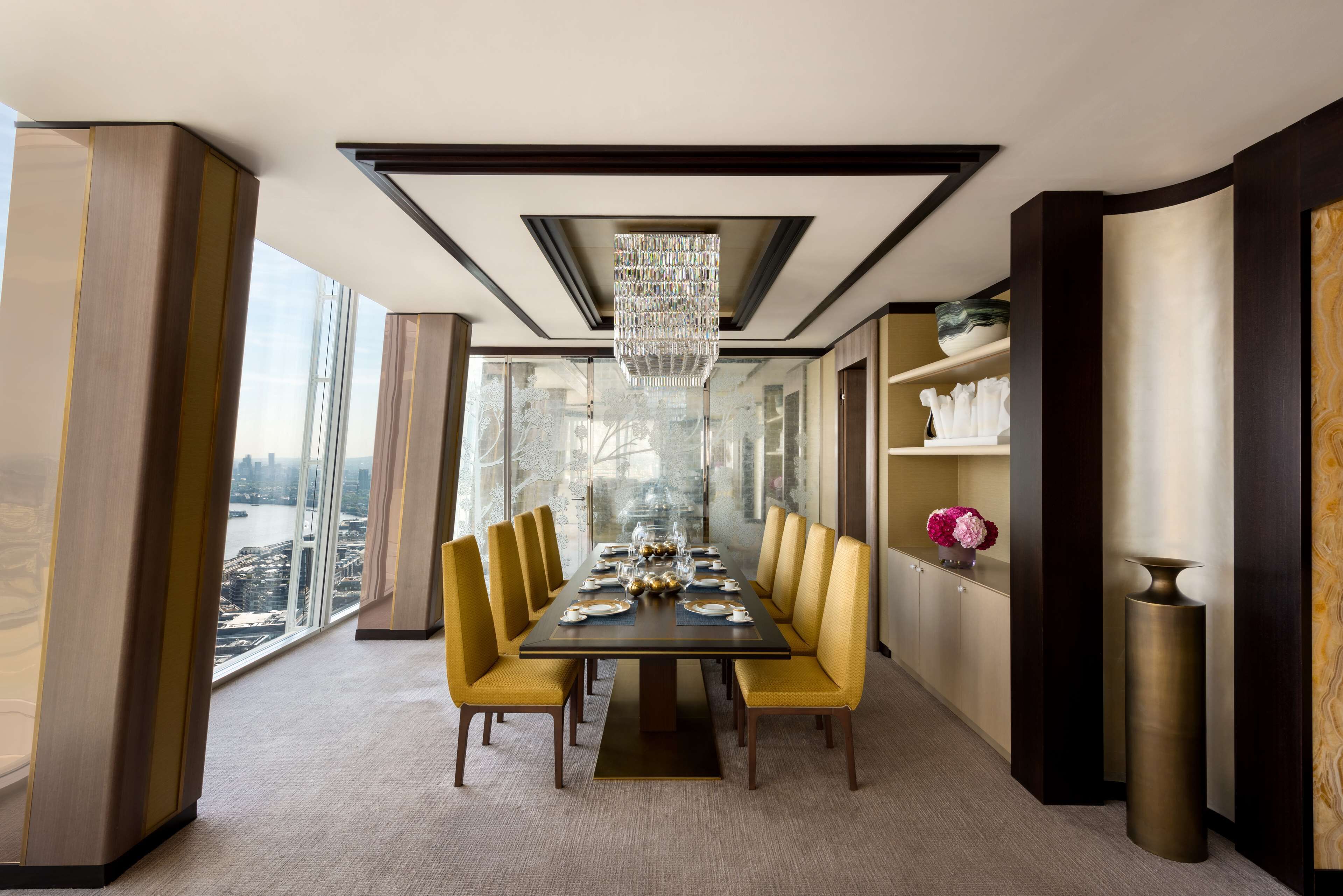 Un comedor moderno con una mesa larga, sillas amarillas y un candelabro.