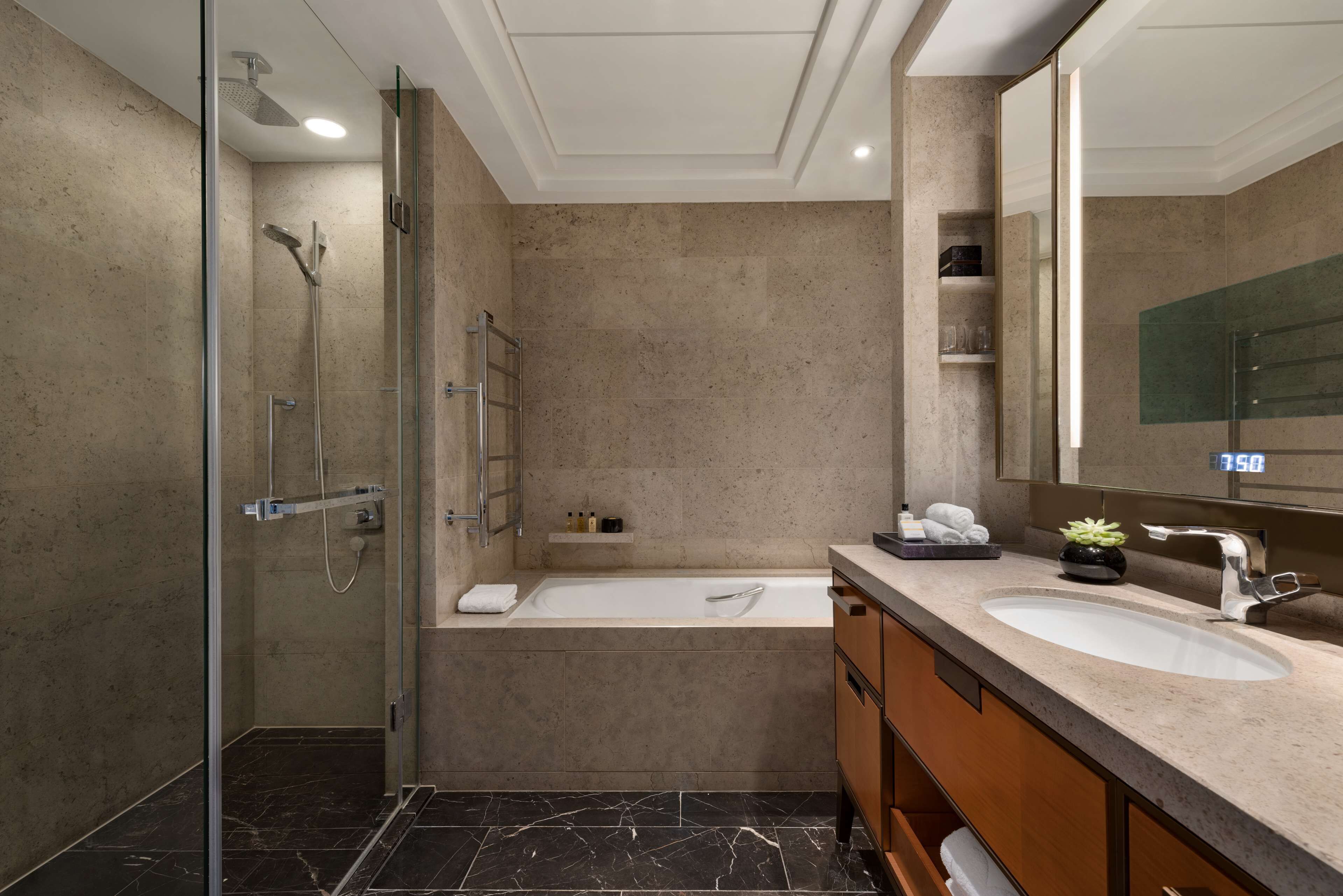 A modern bathroom with a glass-enclosed shower, a freestanding bathtub, and a vanity with a sink and mirror.