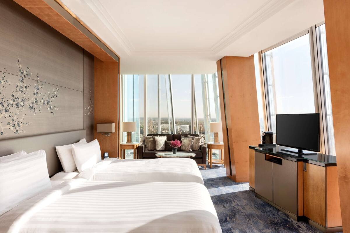 A hotel room with a large bed, a sofa, a TV, and a view of the city.