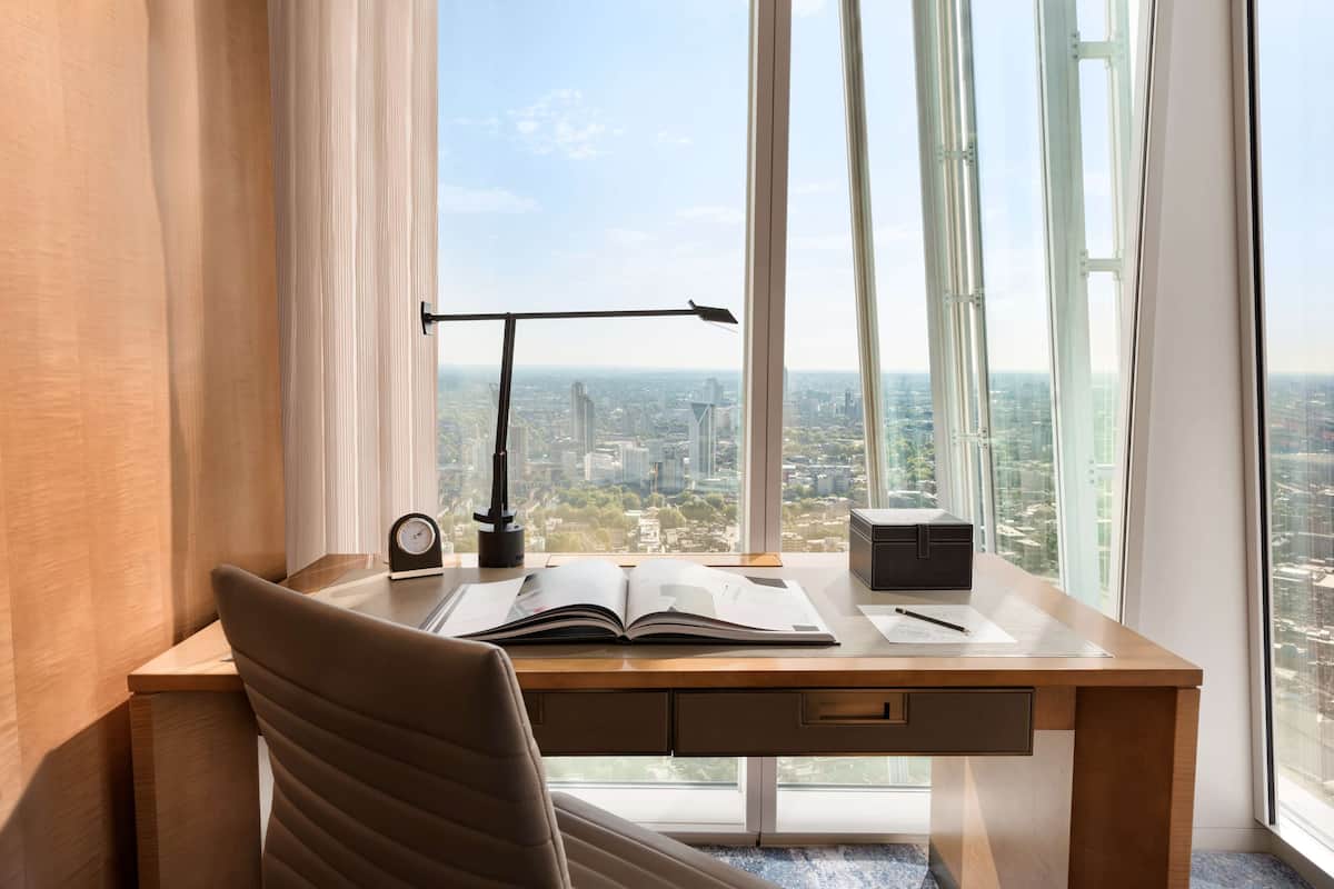 A modern office desk with a city view, a lamp, and an open book.