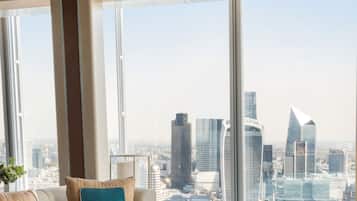 A modern living room with a city view, featuring a sofa with cushions and a framed picture.