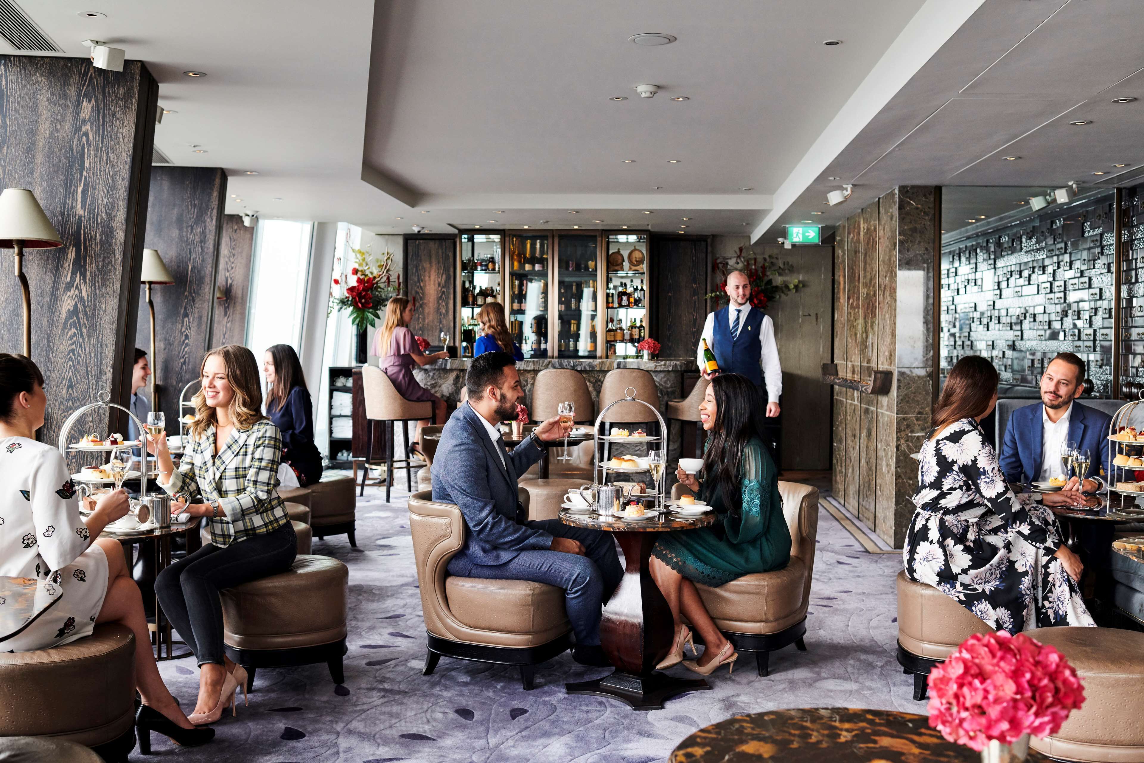 A modern lounge area with seating arrangements, a bar, and a well-stocked bar counter.