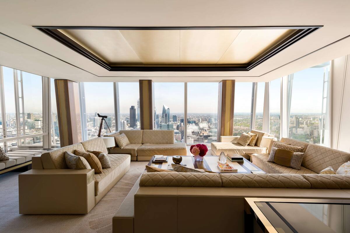 A spacious living room with large windows, a modern ceiling design, and a city view.