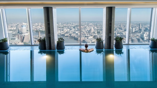 A modern indoor pool with a city view, large windows, and potted plants. - Shangri-La The Shard, London (London)