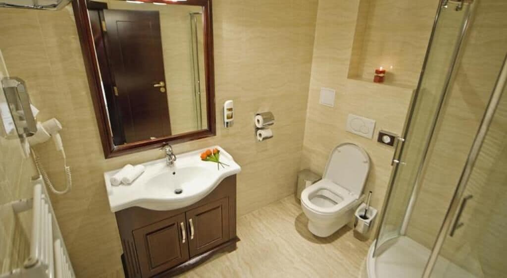 Et badeværelse med vask, spejl, toilet og brusebad.