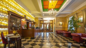 A lobby with a checkered floor, a reception desk, a bar area, and red leather seating.