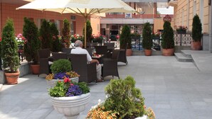 An outdoor seating area with wicker furniture, potted plants, and a large umbrella.