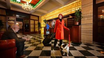 A hotel lobby with a checkered floor, a chandelier, and a reception desk.