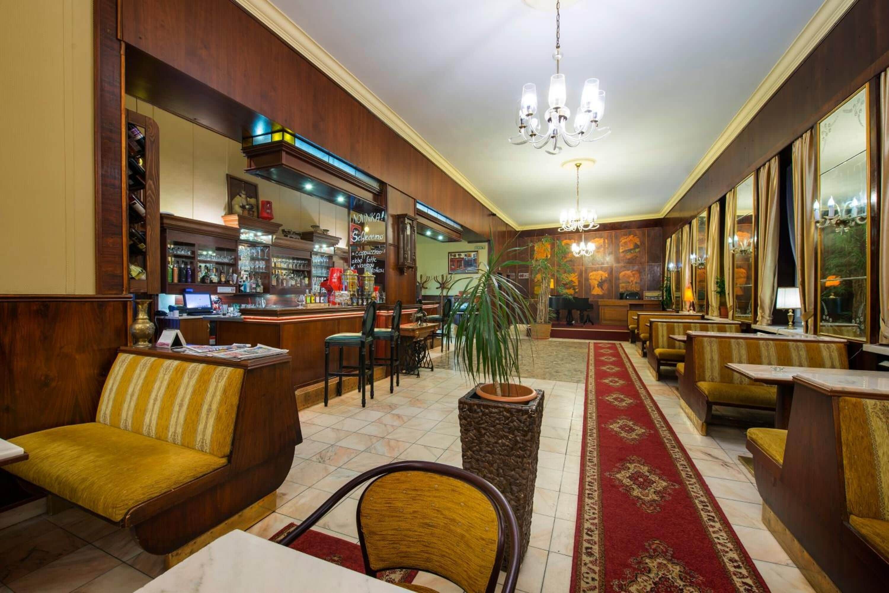 A hotel lobby with wooden furniture, a bar area, and a chandelier.