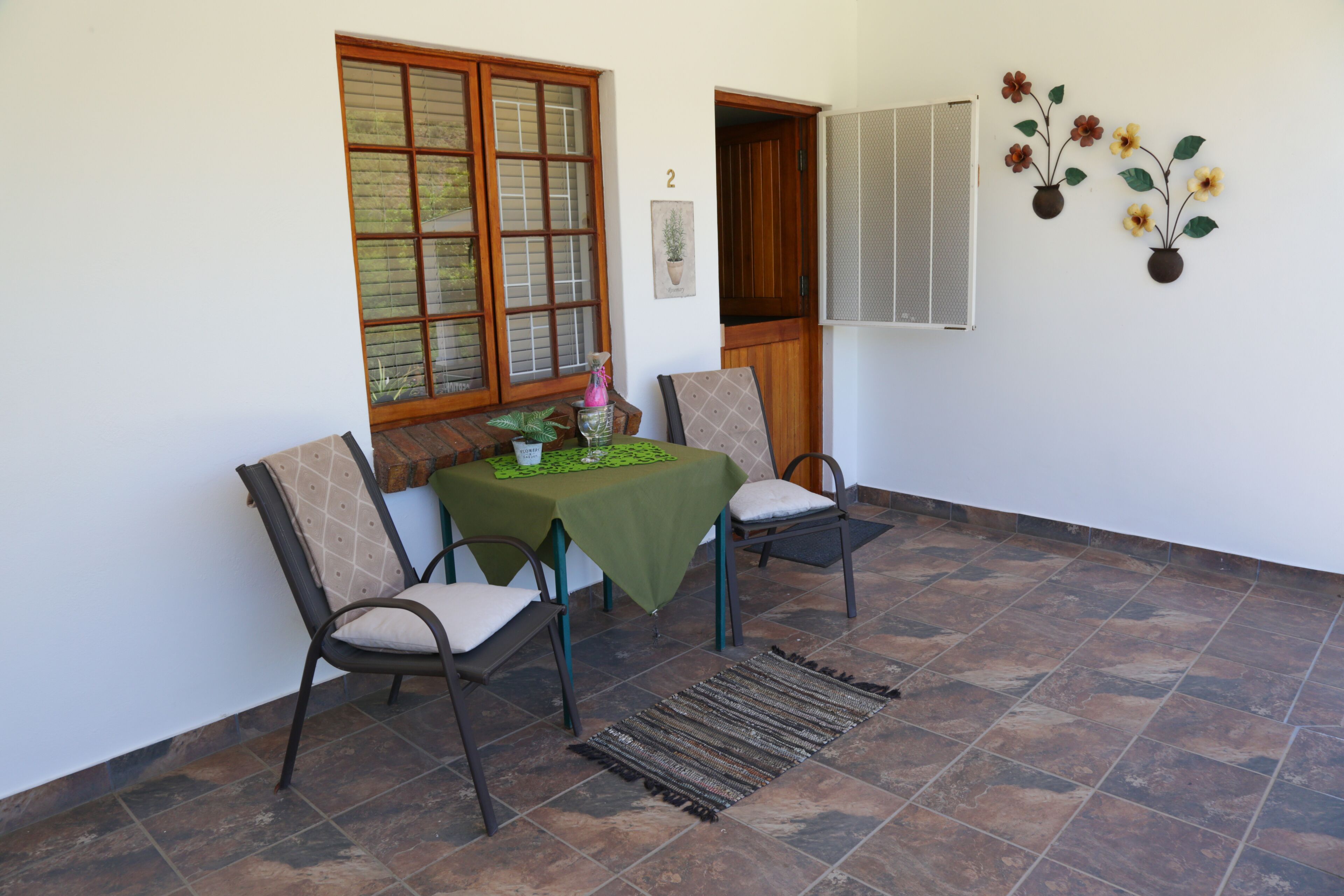 Un comedor con una mesa dispuesta para dos, sillas, una ventana con persianas y un aire acondicionado de pared.