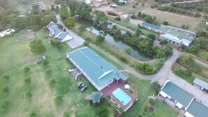 An aerial view of a residential area with multiple houses, a swimming pool, and a river.