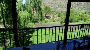 A balcony with a view of a river and greenery, a table with a placemat, and a potted plant.