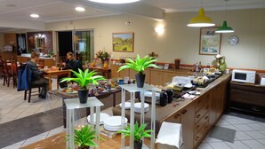 A restaurant with a buffet setup, including a counter with food items and a seating area with tables and chairs.