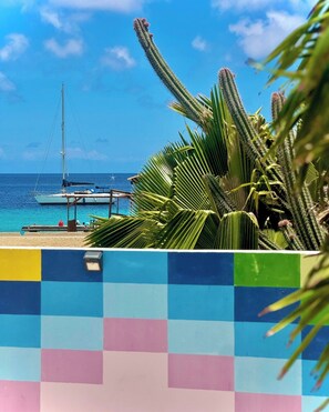 Une plage avec un voilier, des palmiers et une clôture aux couleurs vives.