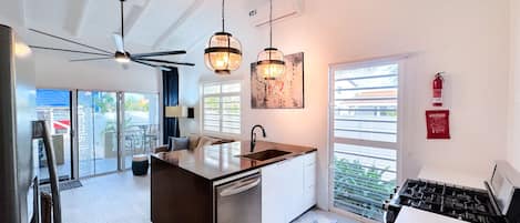 Una cocina moderna con una isla central, luces colgantes y vistas al exterior.